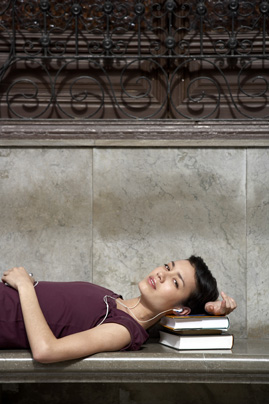 Young woman lying on bench, resting head on books, portrait, close-up