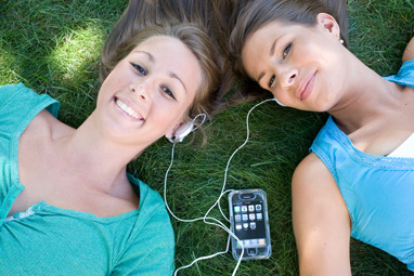 Teenage girls sharing personal stereo
