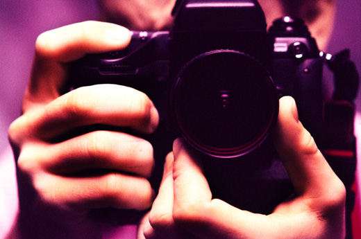 Close-up of human hands holding a camera (toned)